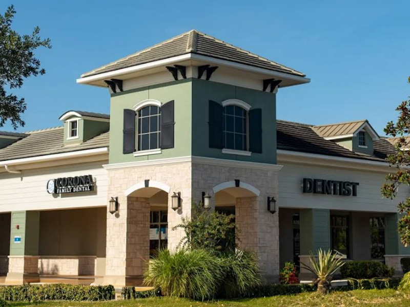 The image shows a two-story building with a flat roof, featuring a prominent overhang with a triangular pediment supported by columns, and a sign with the name  Town Center Medical Plaza  on the front. The architecture suggests a modern design, and there are palm trees visible in the background, indicating a warm climate.