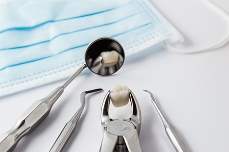 The image shows a collection of dental tools on a white surface with a blue surgical drape and a toothbrush in the center, all under a magnifying glass.