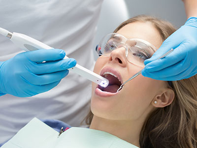 A woman receiving dental care while lying down with a medical device attached to her mouth.