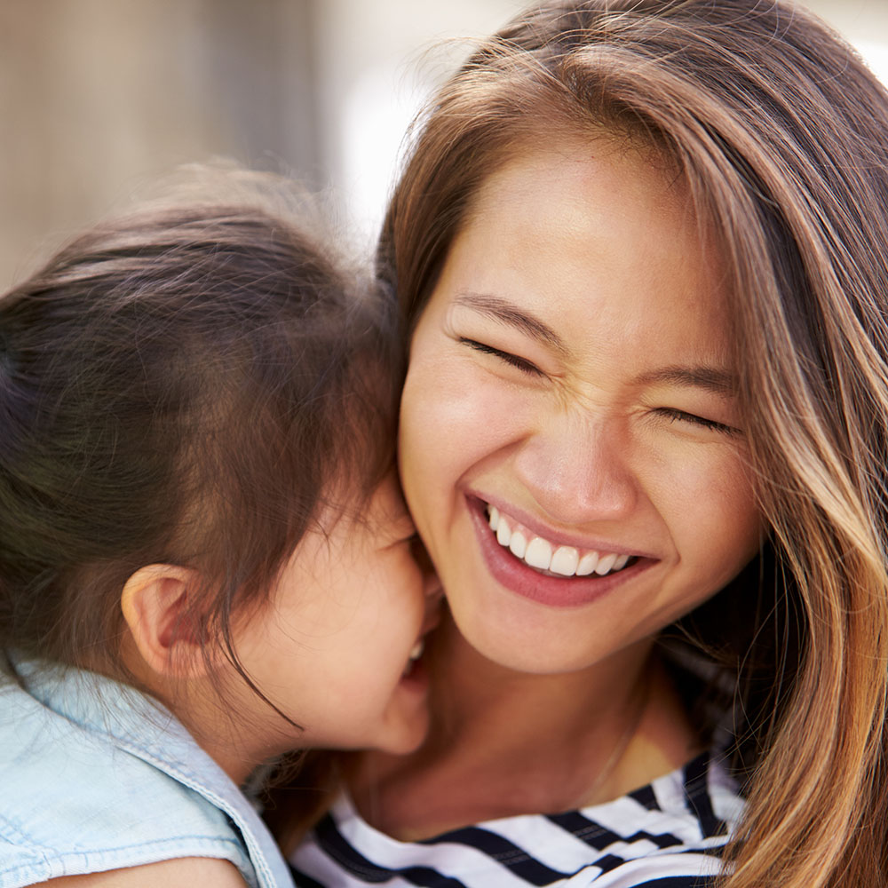 A woman with an infant is smiling at each other, sharing a joyful moment.