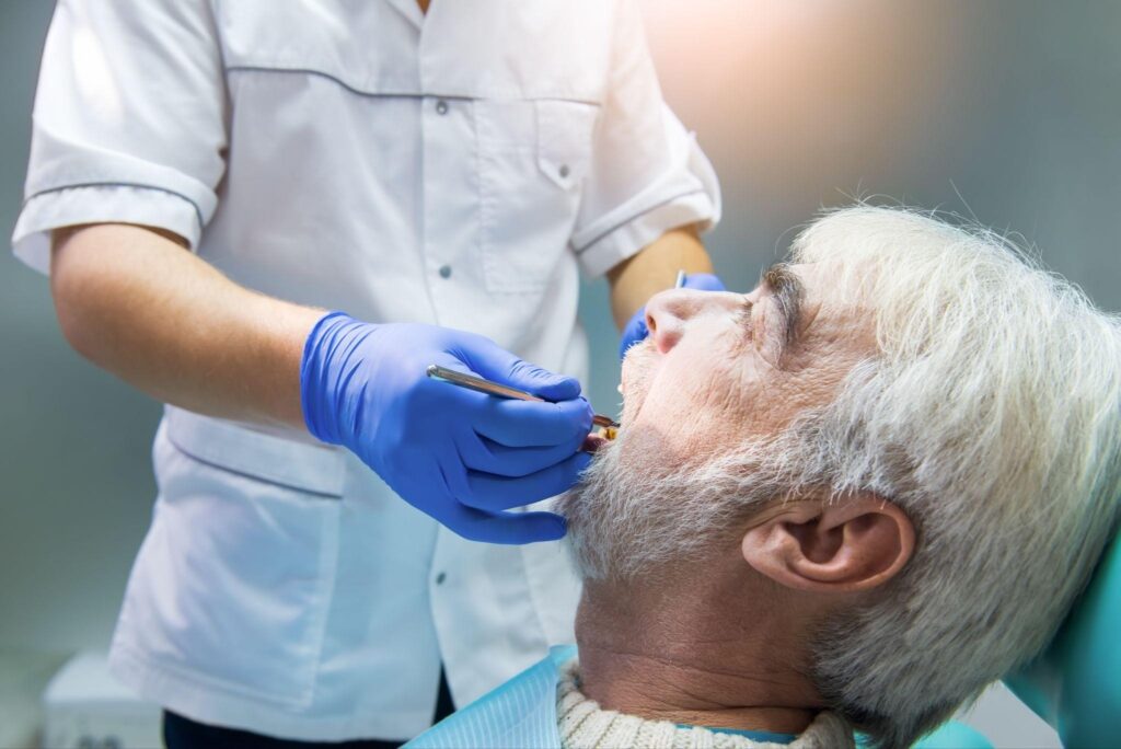Dentist evaluating a senior patient’s teeth during a restorative dentistry Bradenton visit while reviewing dental implant options.